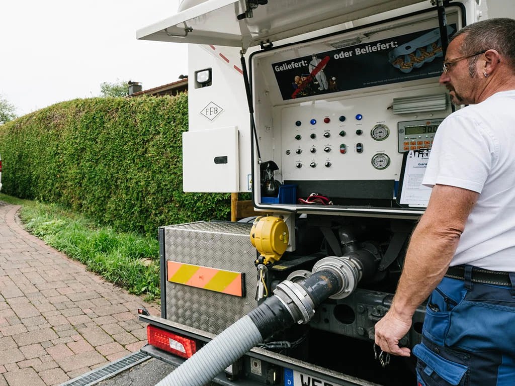 Fahrer bedient die Liefertechnik am Silowagen beim Befüllen